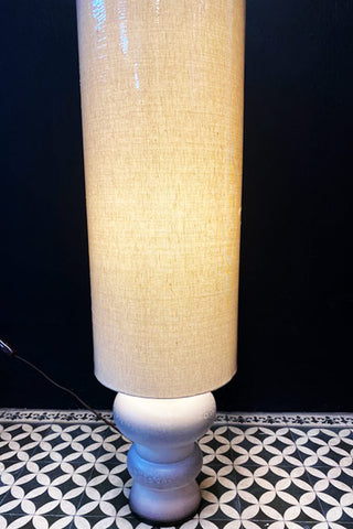 A lit lampshade in an off-white colour.