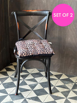 Leopard print seat cushion on a dining chair with a big pink badge that reads 'set of 2'.