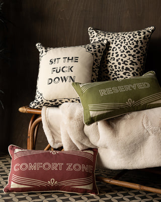 Stacked image of four cushions on a wicker bench. The colourful cushions include a red one with the words 'comfort zone'.