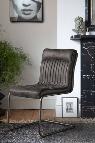 The Ribbed Antique-Style Black Leather Chair styled on a rug in a living room, with various home accessories and a plant.