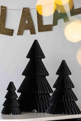 Lifestyle image of the Set Of 3 Black Honeycomb Christmas Trees with a fa la la la sign