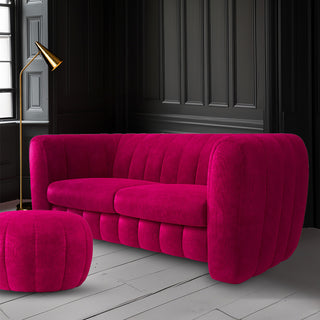 A hot pink sofa and footstool in a dark living room.