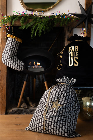 The Star Printed Christmas Sack styled in front of a fireplace with another sack and stocking