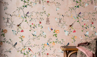 The Rockett St George Modern Chinoiserie Watermelon Blush Wallpaper on the wall, with a bench/throw at the side of the shot.