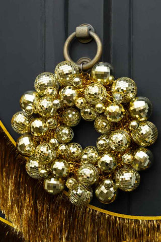 Gold disco ball wreath hanging on a brass door knocker.