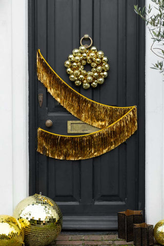 Gold fringe garland on a black door. The door is also styled with a disco garland.